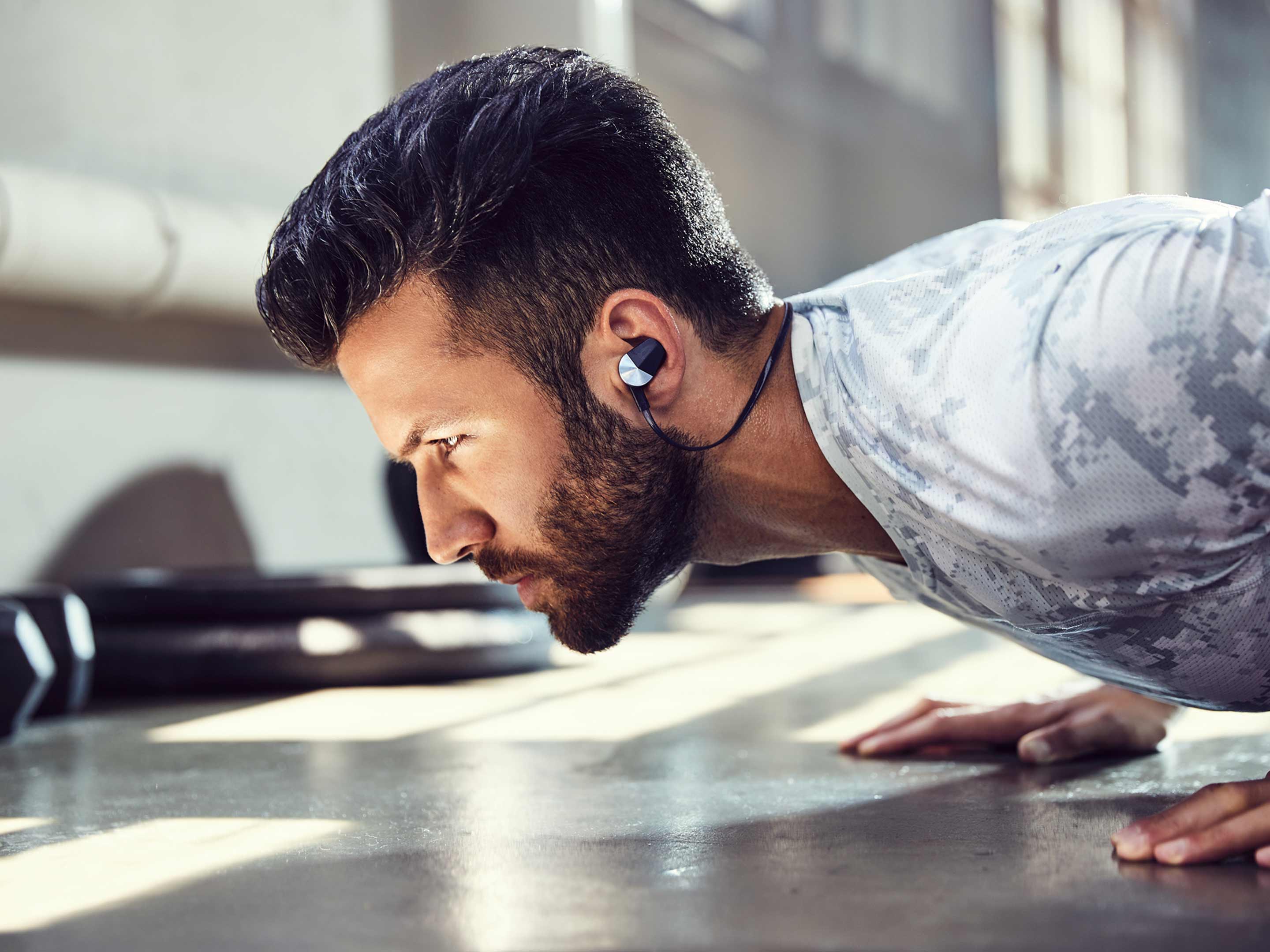 Man doing pushups while Fitbit Flyer headhphones