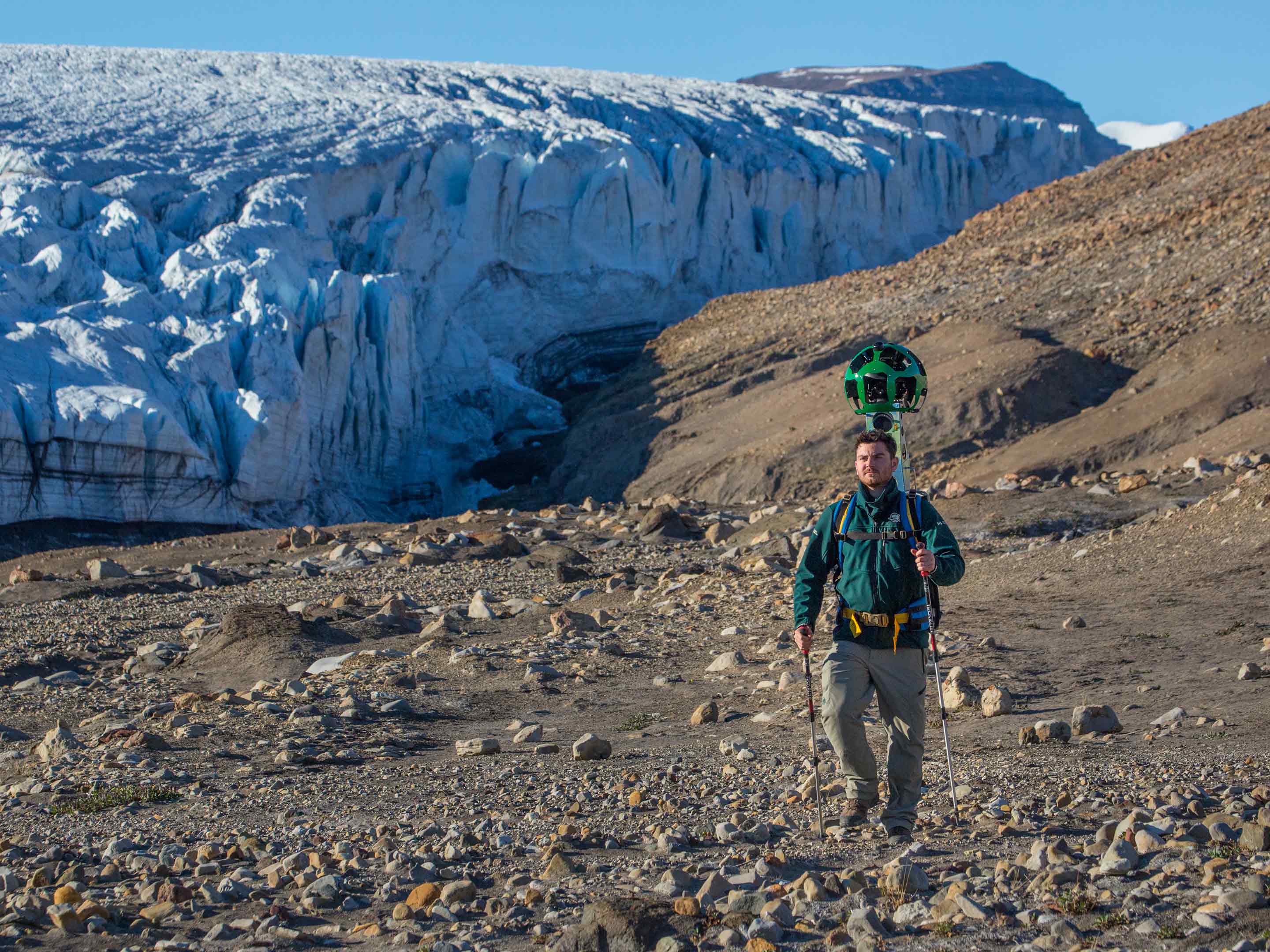 quttinirpaaq national park trekker walking with a glacier behind him 